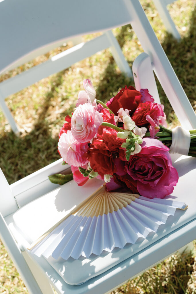 Accordian fan for a outdoor Texas wedding pictured with pink bouquet.