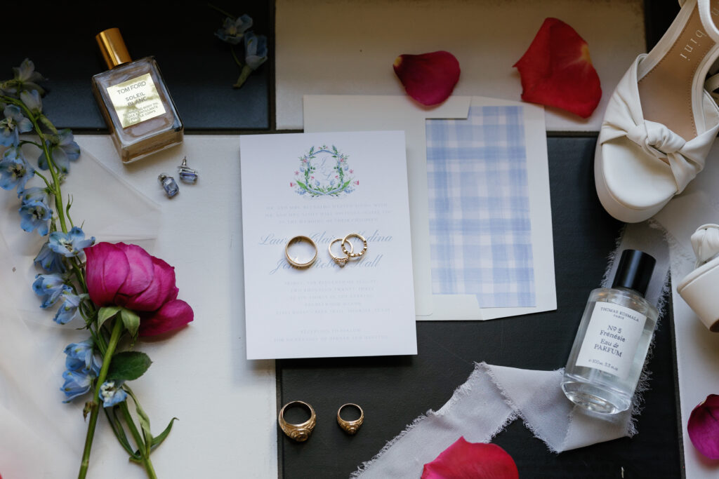 Wedding invitation suite pictured with their wedding rings and class rings.