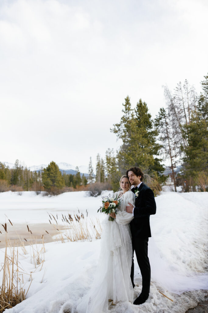 A Texas bride & groom pictured in the snow with mountain peaks in the backrgound.