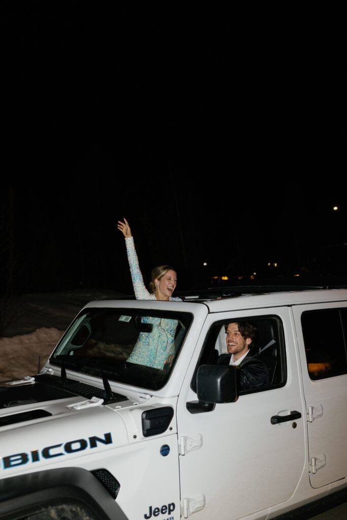 A bride and groom leaving their wedding in a jeep surrounded with snow after their Colorado destination wedding.